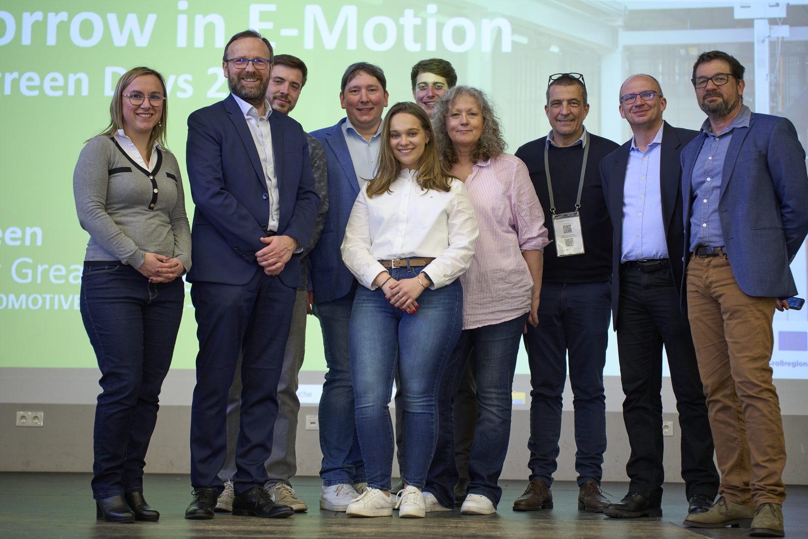 Group photo of organisers and speakers on stage in front of the slide 